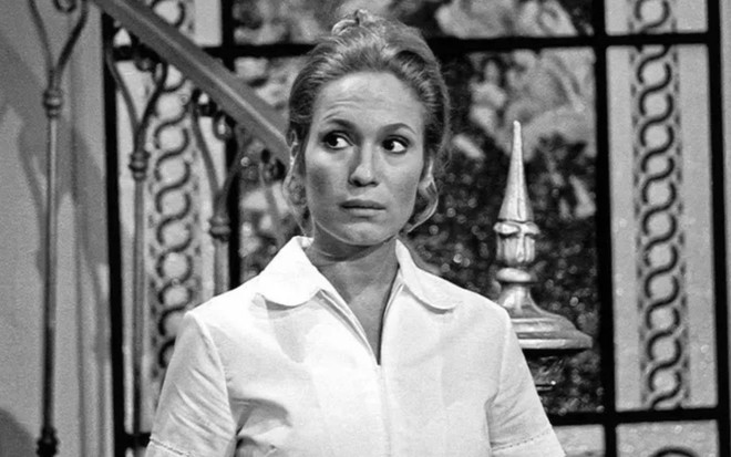Susana Viera usa uniforme de babá e está com a expressão séria em cena preto e branca da novela Anjo Mau (1976)