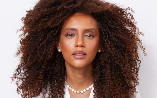 Imagem de Taís Araujo de cabelo solto e camisa branca