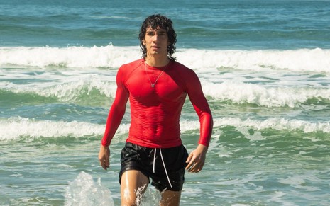 Jorge López anda para fora do mar em cena da série Temporada de Verão