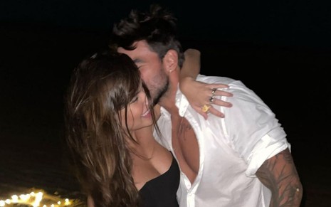 Thaís Braz recebe um beijo na bochecha de Guilherme Napolitano em praia