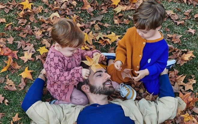 Imagem de Thales Bretas entre os filhos Romeu e Gael em ensaio fotográfico