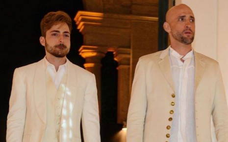 Imagem de Thales Bretas e Paulo Gustavo com ternos brancos durante cerimônia