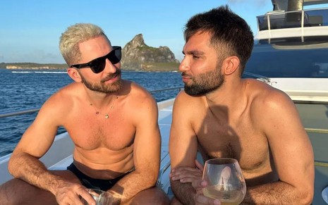 Thales Bretas olha para Silva; os dois estão em um barco em Fernando de Noronha