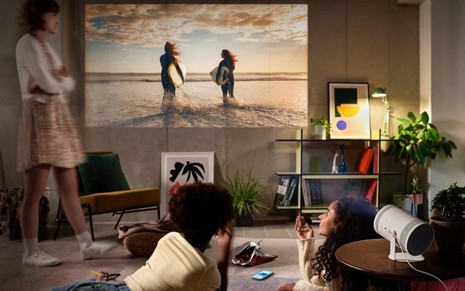 Jovens vendo as imagens do novo projetor portátil Samsung na parede da sala