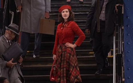 Rachel Brosnahan faz pose na escada de vestido vermelho em cena da temporada final de The Marvelous Mrs. Maisel