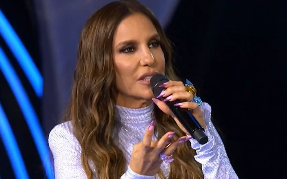 Ivete Sangalo faz um sinal de quatro na mão enquanto apresenta o The Masked Singer Brasil na Globo