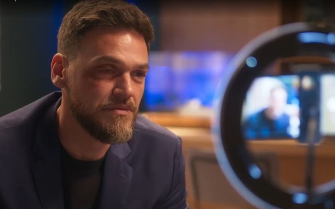 Em cena de Vai na Fé, Emilio Dantas está em frente a um celular preso a uma ring light