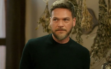 Em cena de Vai na Fé, Emilio Dantas olha para alguém de forma enfurecuda; ele usa blusa preta
