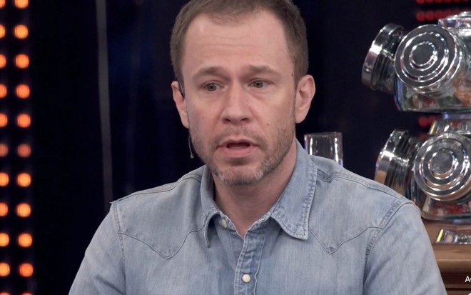 Tiago Leifert com cara séria durante o Domingão com Huck, de camisa jeans azul clara