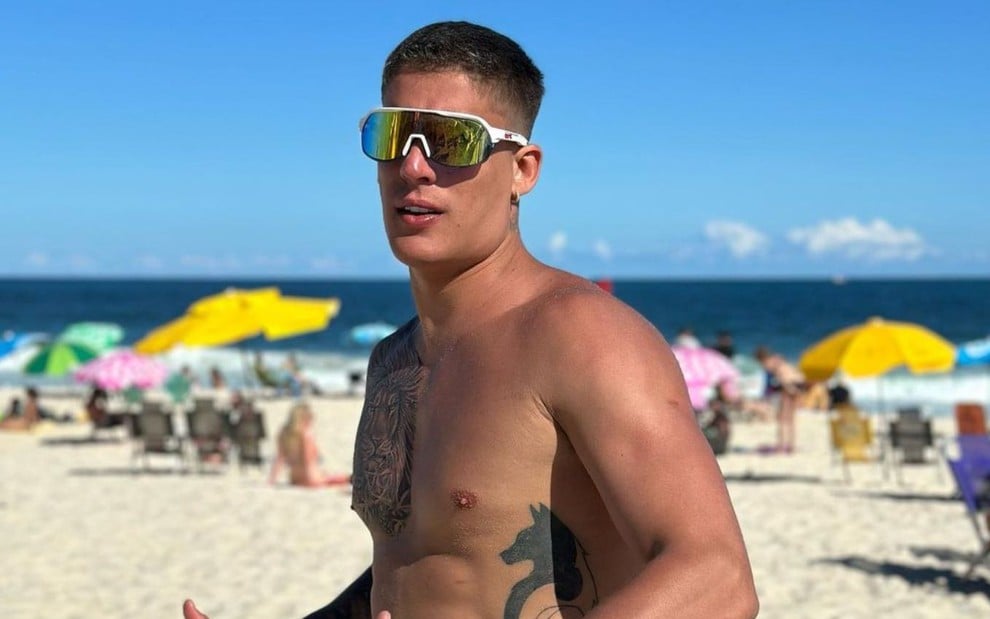 Imagem de Tiago Ramos, sem camisa, na praia