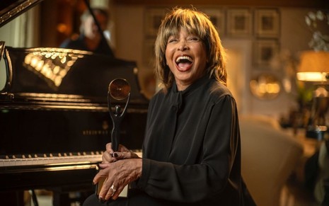 Tina Turner sorri abertamente enquanto segura seu prêmio do Hall da Fama do Rock 'n' Roll