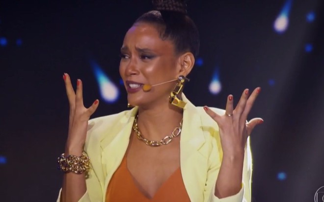 Imagem de Taís Araujo de cabelo preso na bancada de jurados do The Masked Singer Brasil