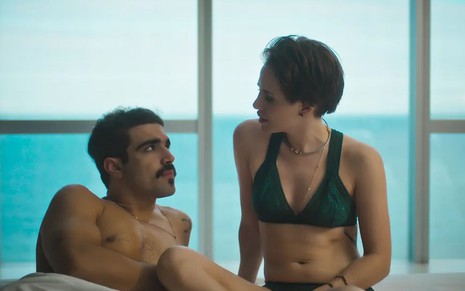 Os atores Caio Castro e Leticia Colin como Pablo e Vanessa em Todas as Flores; eles estão na cama, um ao lado do outro, conversando e se olhando, seminus