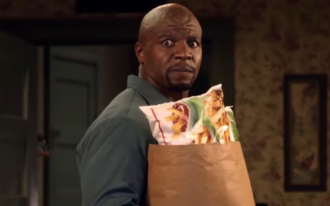 Imagem de Terry Crews como Julius na série Todo Mundo Odeia o Chris enquanto segura uma sacola de supermercado