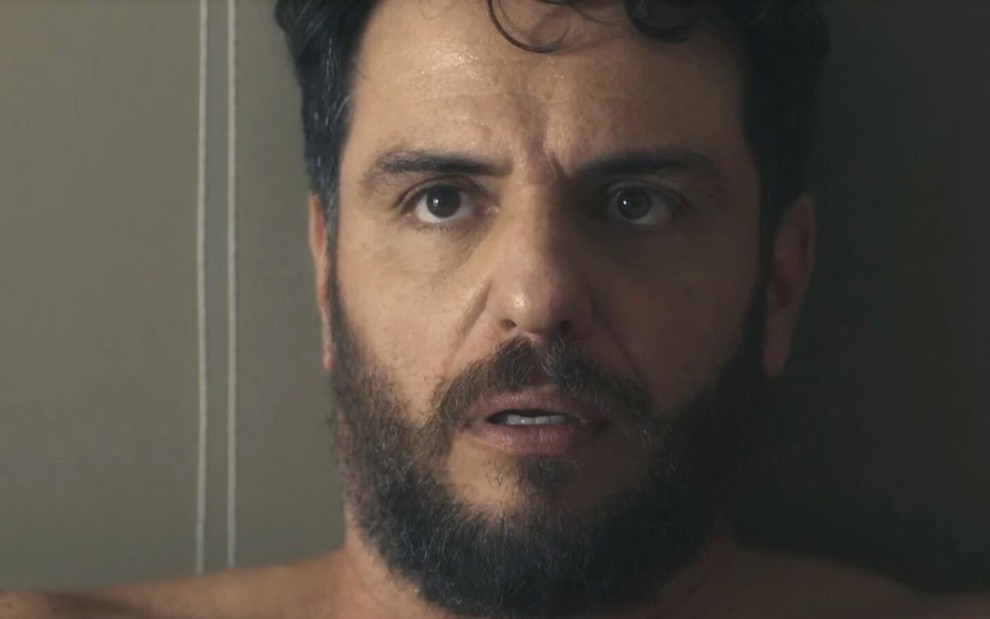 Rodrigo Lombardi interpreta Moretti em Travessia; ele está sem camisa e com cara de assustado