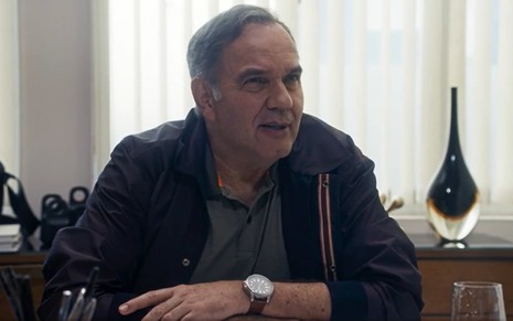 Humberto Martins com sorriso discreto em cena como Guerra na novela Travessia
