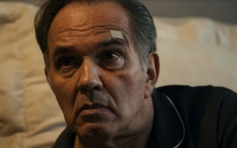 Em cena de Travessia, Humberto Martins está com um curativo acima da sobrancelha e está olhando para alguém