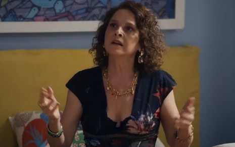 A atriz Drica Moraes com braços abertos, expressão de indignação, em cena da novela Travessia