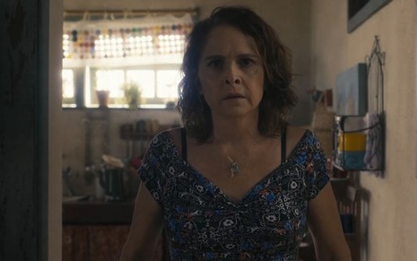 A atriz Drica Moraes como Núbia em Travessia; ela está parada em pé, olhando para frente com cara de espantada
