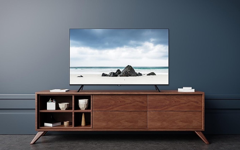 TV de 65 polegadas apoiada em um móvel de madeira