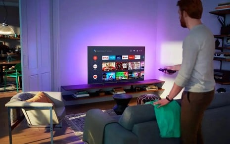 Homem navegando pelo menu do sistema Android TV em um televisor Philips