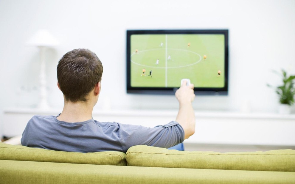 Torcedor vê partida de futebol na TV da sala