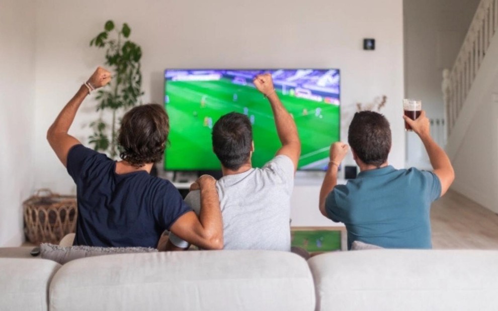 Amigos assistem a jogo da Copa em TV de tela grande