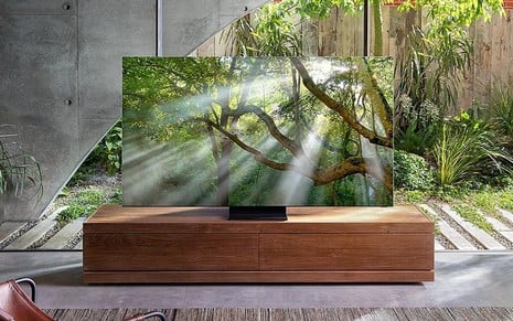 TV QLED instalada sobre o móvel de uma sala que se comunica com o jardim