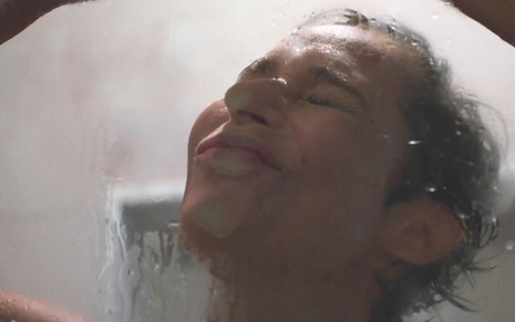 Andrea Beltrão com o rosto colado no box do chuveiro em cena de Um Lugar ao Sol, da Globo