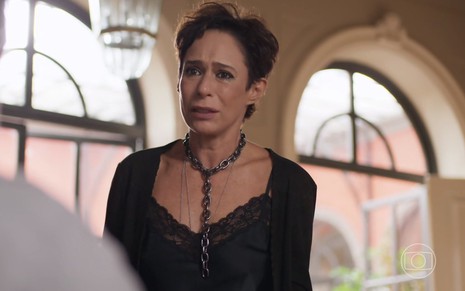 A atriz Andrea Beltrão chora em cena na qual usa blusa e casaco pretos na pele de Rebeca, sua personagem em Um Lugar ao Sol