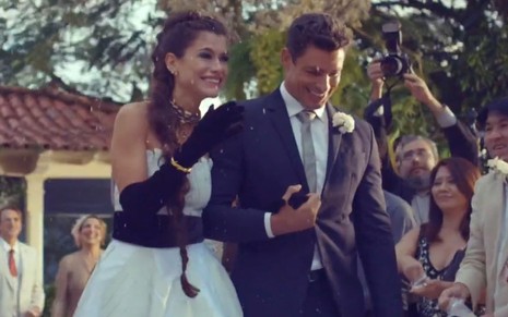 Cauã Reymond e Alinne Moraes estão caracterizados como Christian e Bárbara; os dois estão vestidos de noivo durante cena de casamento em Um Lugar ao Sol