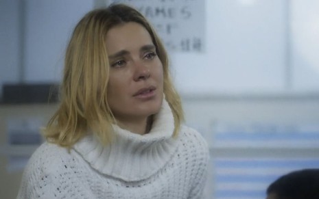Em cena de Vai na Fé, Carolina Dieckmann usa um tricô branco de gola alta e parece estar chorando