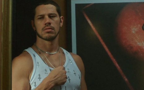 Em cena de Vai na Fé, José Loreto usa camiseta branca e está chorando, encostado a uma parede