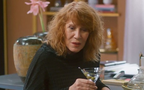 Renata Sorrah segura copo de drink na mão em cena como Wilma na novela Vai na Fé
