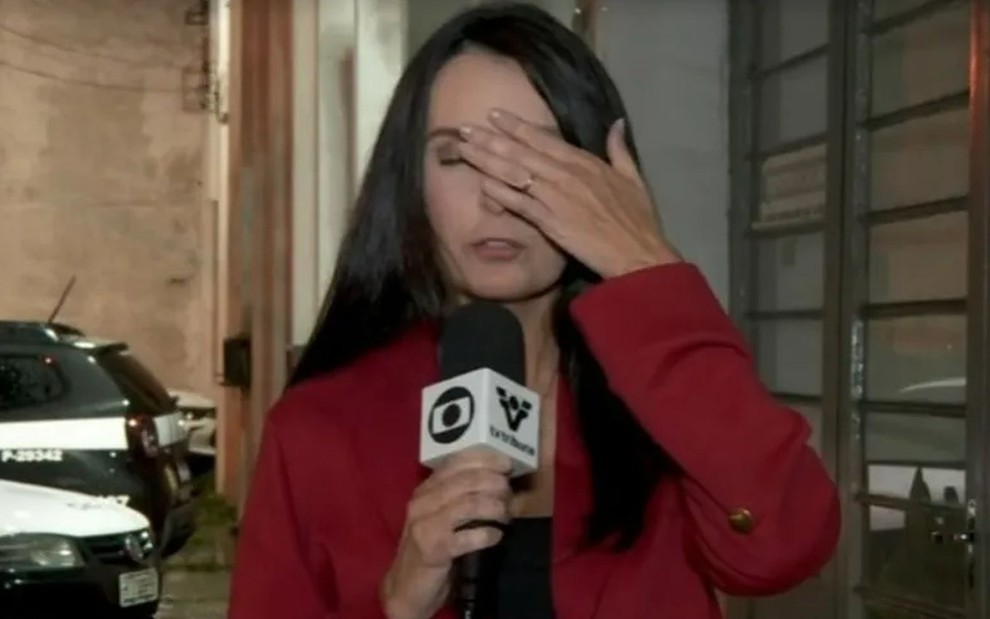 A repórter Vanessa Medeiros durante link para o JT2, na TV Tribuna; ela está segurando um microfone, de frente a uma câmera, com os olhos fechados e a mão no rosto