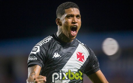 Jogador Raniel, do Vasco, grita ao comemorar gol e veste uniforme preto com faixa diagonal branca