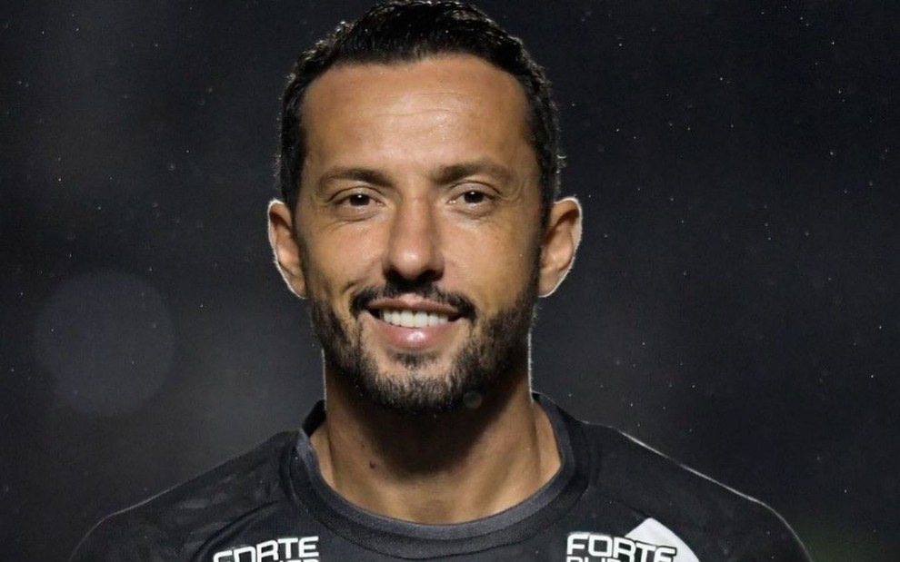 Jogador Nenê, do Vasco, comemora gol sorrindo e veste uniforme preto com faixa diagonal branca