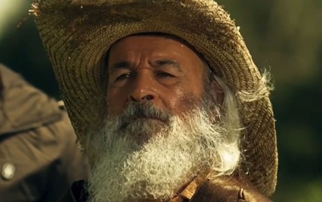 Osmar Prado usa barba longa, chapéu e um manto e está caracterizado como o Velho do Rio para a novela Pantanal