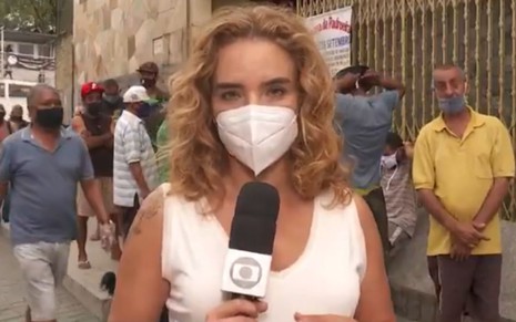 A jornalista Veruska Donato em reportagem na Globo; ela usa blusinha branca e máscara