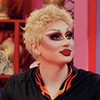 A drag queen Maddy Morphosis com uma peruca curta, loira, e maquiagem pesada com um figurino inspirado no cozinheiro Guy Fieri no Werk Room de Drag Race
