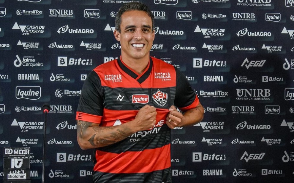 Jadson, meia-atacante, sorri e mostra a camisa do Vitória em sua apresentação oficial pelo clube