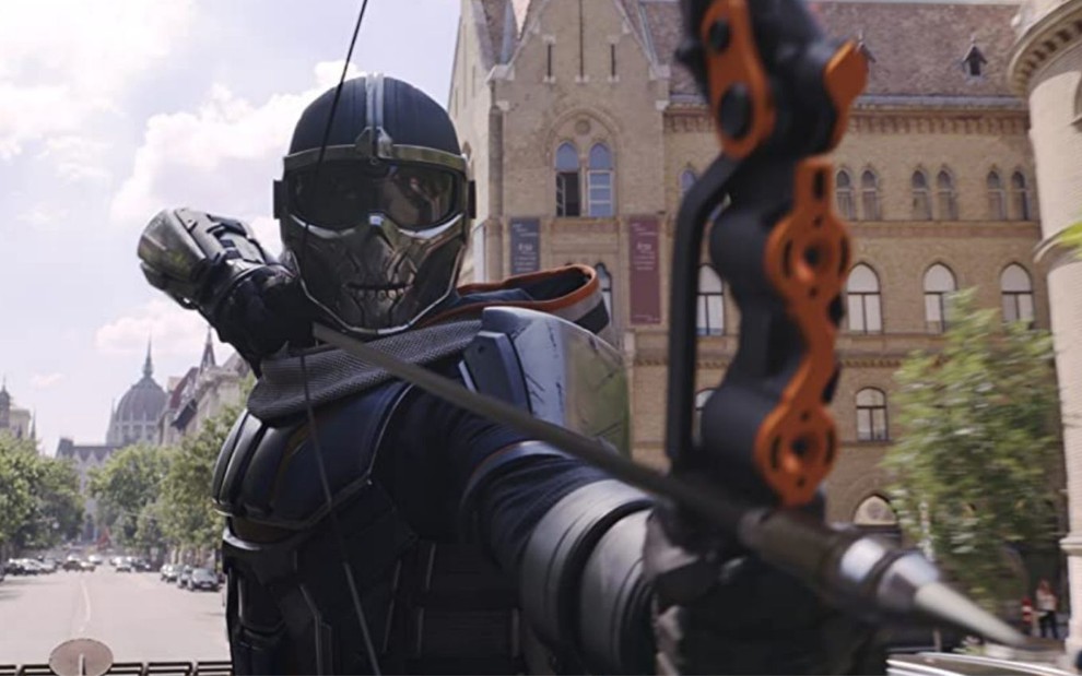 O vilão Treinador atira com arco e flecha em cena do filme Viúva Negra