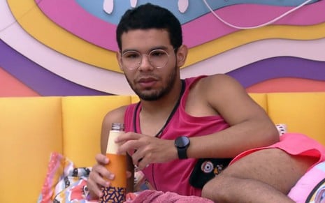 Vinicius Fernandes deitado e conversando em cama do quarto lollipop do BBB 22