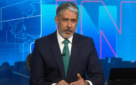 William Bonner com uma gravata verde e terno no Jornal Nacional