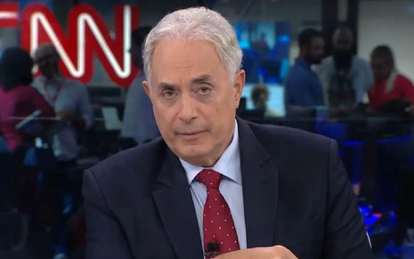 William Waack na CNN Brasil com um terno preto e uma gravata vermelha