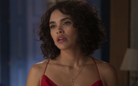 Giovana Cordeiro com expressão séria e usando vestido vermelho em cena como Xaviera na novela Mar do Sertão