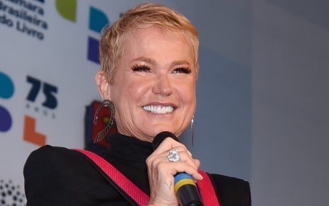 A apresentadora Xuxa segura microfone e sorri em evento em São Paulo realizado em 2022