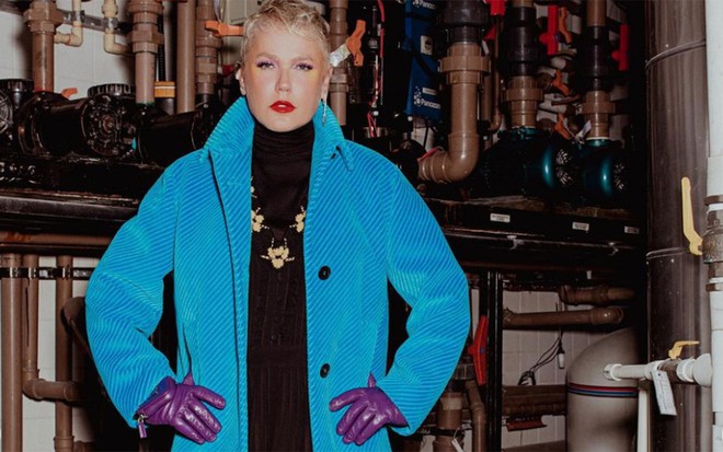 Xuxa Meneghel em ensaio fotográfico da revista Vogue, com casaco de veludo azul e luvas roxas