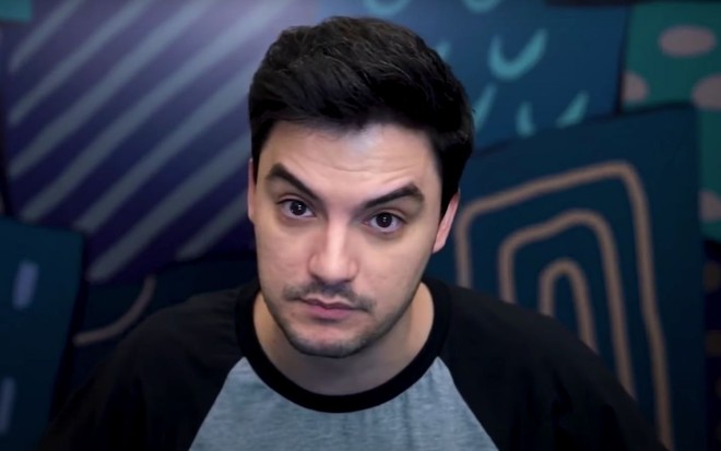 Felipe Neto em vídeo publicado no Youtube: sentado, está de camisa cinza com detalhes pretos e olha para frente