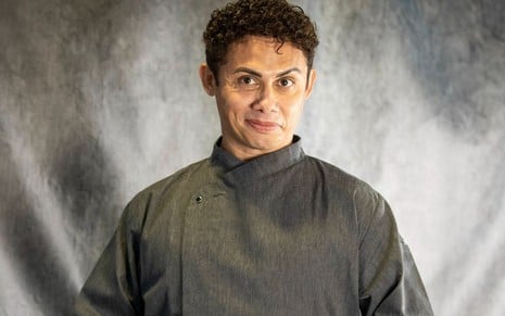Silvero Pereira usa um uniforme de mordomo cinza e está caracterizado como Zaquieu da novela Pantanal